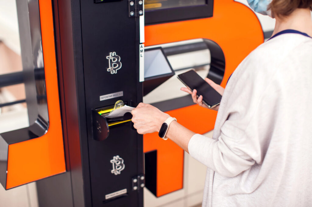 Customer inserting cash into a Bitcoin ATM to buy Bitcoin without using a bank account